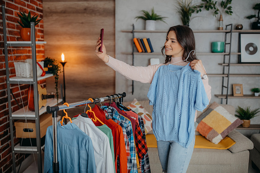 Attractive young woman is choosing clothes in light room. Girl in wardrobe.