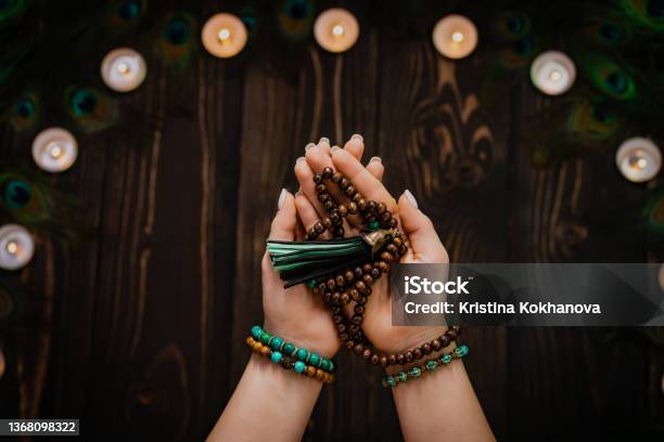 Woman Holds In Hand Wooden Mala Beads Strands Used For Keeping Count During Mantra Meditations Weaving And Creation Wooden Background With Candles And Feathers Spirituality Religion God Concept Stock Photo - Download Image Now