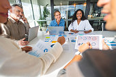 Group of people meeting with technology and paperwork.