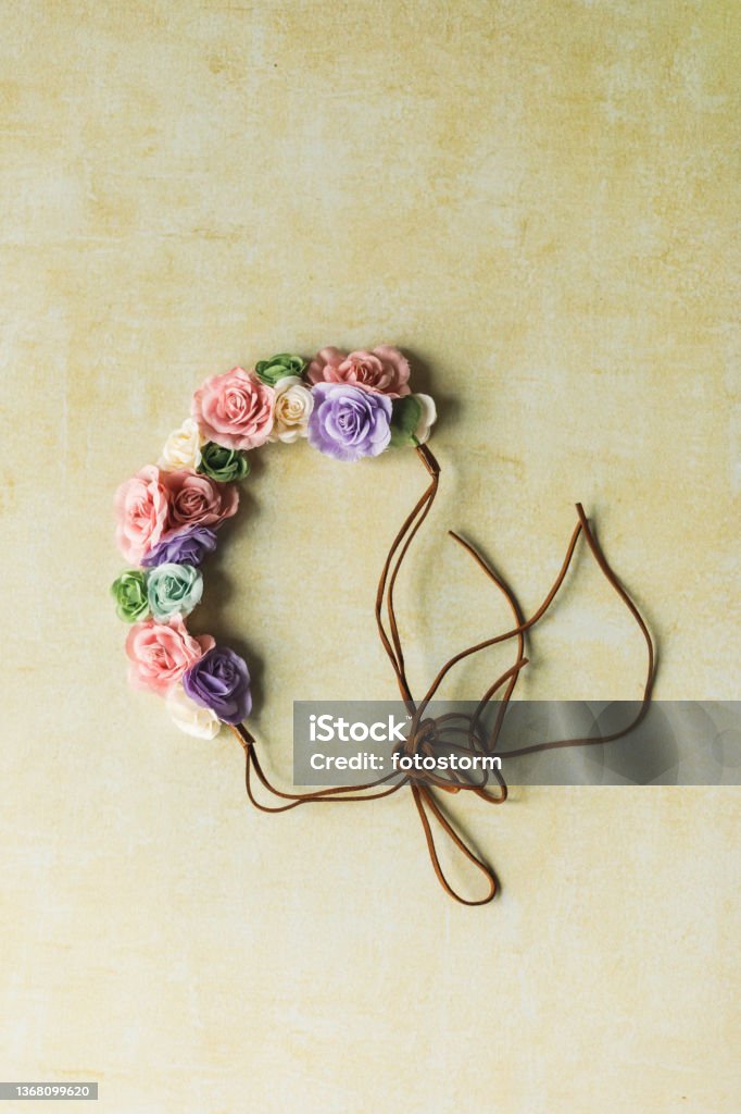 Close up shot of cute little headband with colorful roses Directly above shot of cute little headband with colorful, pink, green, white and purple roses, lying on a pastel yellow background. Floral Crown Stock Photo