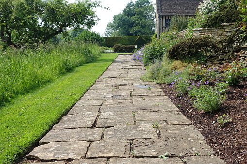 Stone paved garden path with a lawn and flower bed