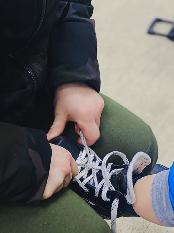 dad tying his son's skates close-up in Dnipro, Dnipropetrovsk Oblast, Ukraine