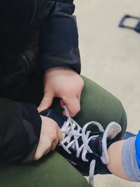 Photo of dad tying his son's skates close-up