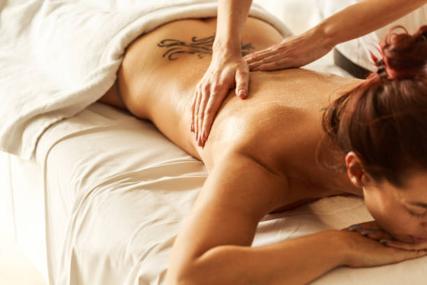 Back massages are great to relief tensions High angle view of naked woman lying down on stretcher and receiving a back massage by a professional in a spa center. back shoulder tattoos for women pictures stock pictures, royalty-free photos & images