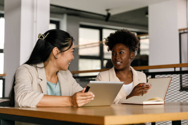 istock Two young businesswomen sitting at table and casually chatting 1368104307
