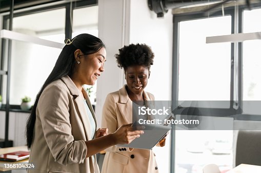 istock Two businesswomen looking at data on digital tablet while going on a meeting 1368104324