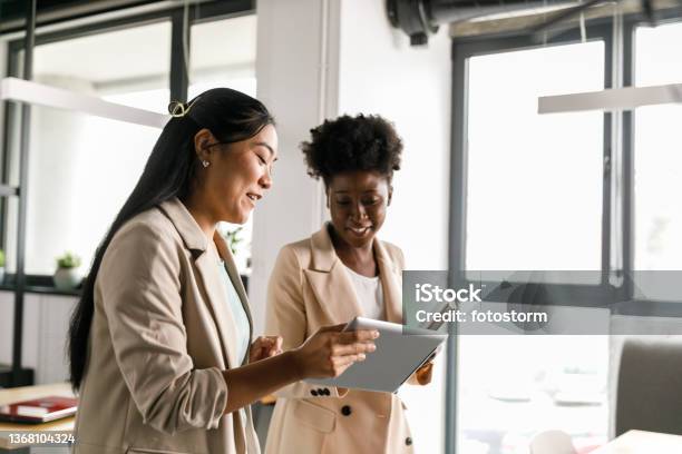 Two Businesswomen Looking At Data On Digital Tablet While Going On A Meeting Stock Photo - Download Image Now
