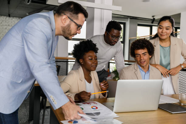 istock Five business people reviewing data on laptop while working together 1368104329