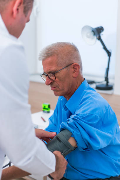 un medico caucasico misura la pressione sanguigna del suo paziente anziano. - patient blood pressure gauge doctor male foto e immagini stock