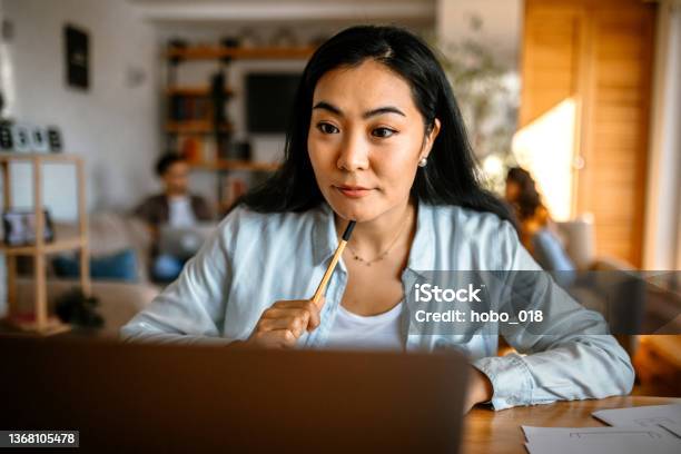 Young Pretty Asian Woman Sitting At The Desk In Her Home Office Doing Home Finances Stock Photo - Download Image Now