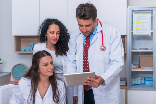 istock Two nurses ( female physicians ) and a male doctor looking in a tablet at the doctor's office while discussing a medical report ( patient's health problems ). 1368105528
