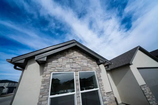 Photo of Cultured Stone and Stucco Home Exterior Detail with Big Window and Garage Door