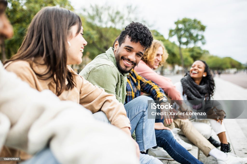 Diverse group of young people laughing and having fun together Diverse group of young people laughing together - Hispanic latin man smiling at camera while having fun with multiracial friends in city street - Friendship, unity and millennial colleagues concept University Student Stock Photo