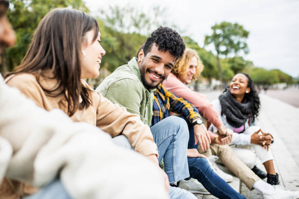 Diverse group of young people laughing and having fun together Diverse group of young people laughing together - Hispanic latin man smiling at camera while having fun with multiracial friends in city street - Friendship, unity and millennial colleagues concept person of color stock pictures, royalty-free photos & images