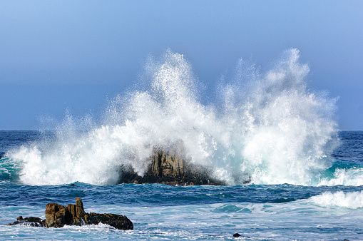 Rocky beach with Atlantic Ocean waves meeting with underwater sharp rocks. Blue sea with small waves with foam crashing on the beach, south of Tenerife, Canary Islands