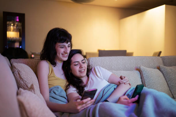 istock Lesbian couple using smart phone and testing filters on the sofa. 1368113137