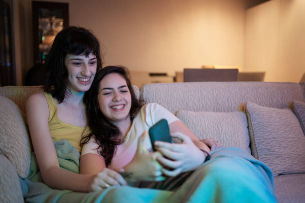 istock Lesbian couple using smart phone and testing filters on the sofa. 1368113168