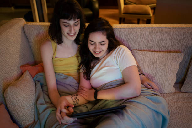istock Lesbian couple watching video on digital tablet on the sofa. 1368113184