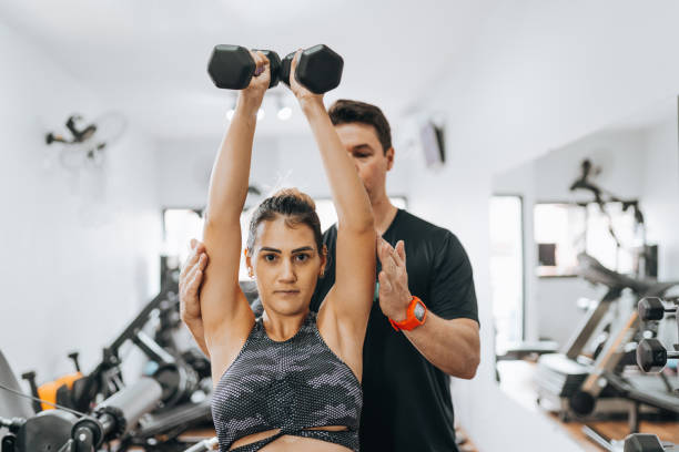 istock Personal trainer correcting arm positioning in weightlifting 1368133418