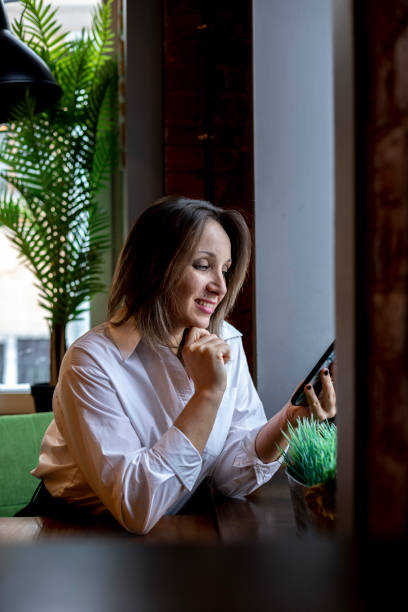 istock Young woman typing message mobile phone while drinking coffee. Businesswoman keeps social distance 1368134746