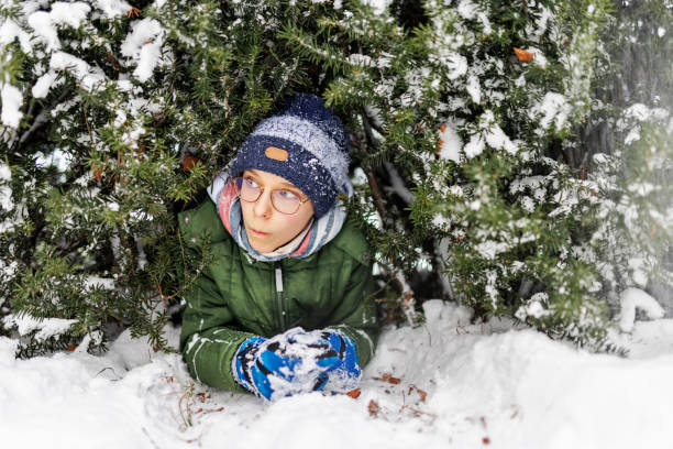 istock Little boy squeezing through the hedge in winter 1368142157
