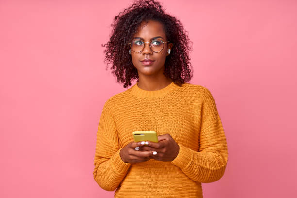 istock Dark skinned woman uses modern cell phone for sending text messages, has thoughtful expression 1368142195