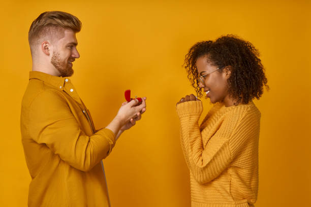 istock Handsome man making a proposal to happy dark skinned woman with ring box 1368142765
