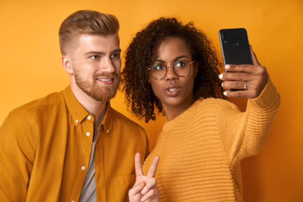 istock Studio shot of overjoyed couple laughs sincerely while poses for selfie 1368143026