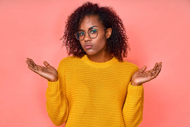 istock Confused woman with dark skin spreads hands sideways, smirk face, feels doubt while makes choice 1368143113