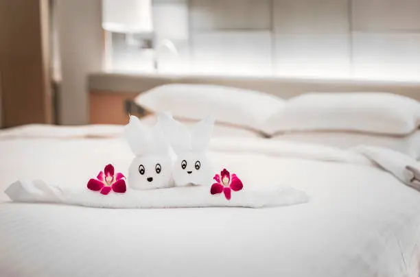 Hotel resort bed with towel art design shaped as a bunny sculpture in a flower basket with orchids