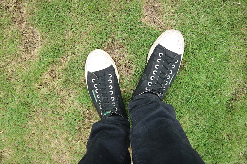 man wearing black pants and black shoes standing on the grass photo