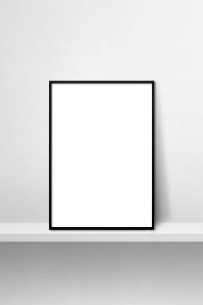 istock Black picture frame leaning on a white shelf. 3d illustration. Vertical background 1368150921