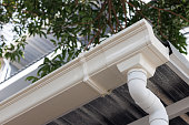 istock white plastic rain gutter of roof of house. vinyl rain gutter and downpipe. 1368151166