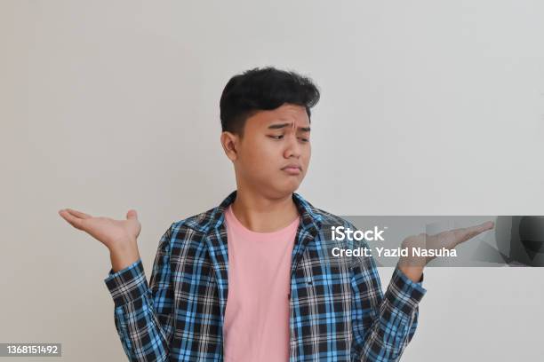 Confused Asian Man Choosing Between Two Different Options Stock Photo - Download Image Now