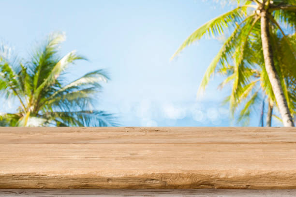 Wood table top with blurred sea and coconut trees background stock photo