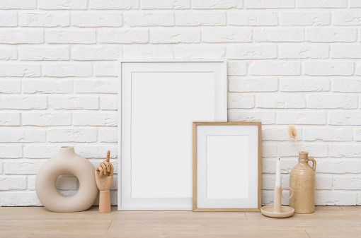 Blank picture frames mockup on floor near white brick wall