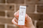 Hands holding Covid-19 rapid antigen test cassette with positive result of rapid diagnostic test