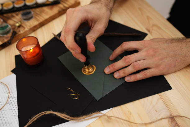 masculine hands sealing dark green envelope with wax stock photo