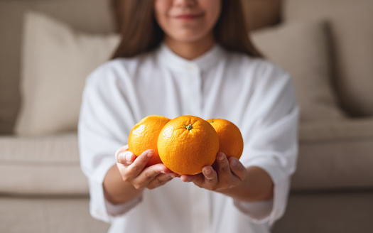 Young beautiful woman holding slice of orange and looking at camera