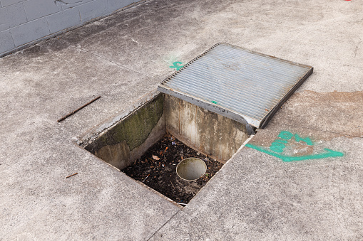 Uncovered drain with rubbish including a syringe