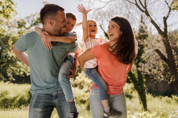 istock Playful family having fun while piggybacking in springtime. 1368157089