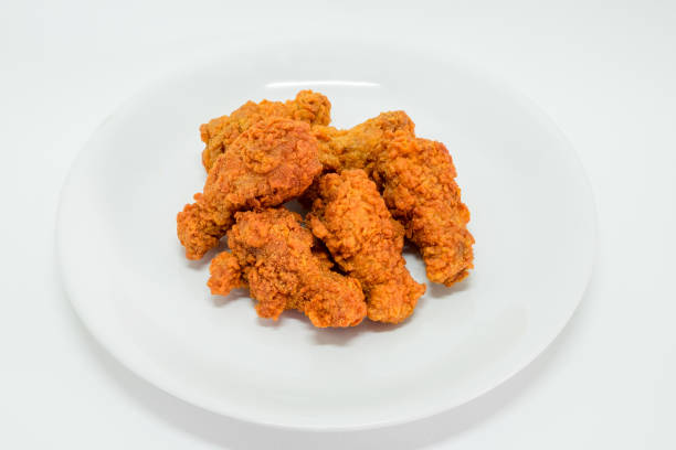 Hot fried chicken wing spicy in plate on white background. Delicious southern Kentucky drumstick crunchy meal. Recipe fast food pieces.