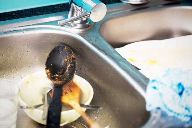 A collection of dirty plates and cups fills a kitchen sink area.