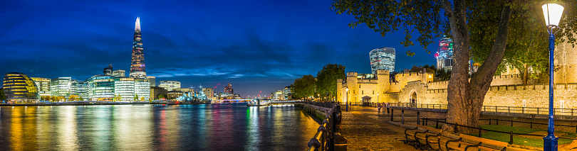 Panoramic view along the River Thames at dusk reflecting the illuminated skyline of City Hall and The Shard in the heart of the UK's vibrant capital city.
