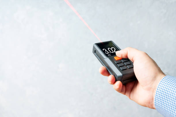 Laser rangefinder or laser tape measure in a male hand. It is a smart device for quick measurement of a distance. Background with copy space. stock photo