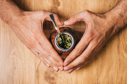 Mate tea in calabash in the hands of a heart