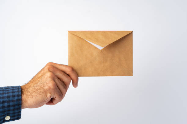 istock Male hand holding small envelope against the white surface 1368165385