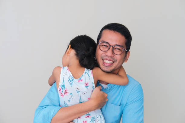 Asian father smiling happy while hugging his daughter Asian father smiling happy while hugging his daughter keluarga stock pictures, royalty-free photos & images