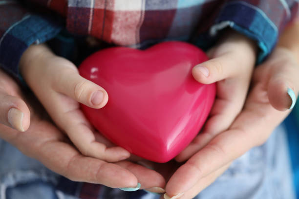 istock Woman and child hands holding red toy heart closeup 1368167659