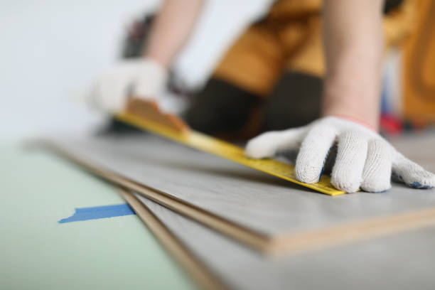 istock Man builder measuring laminate board with ruler for laying floor closeup 1368167664